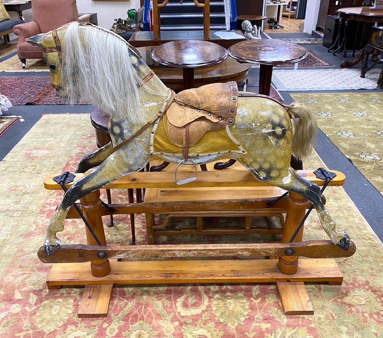 An early 20th century Ayers type dapple rocking horse with tan leather tack on pine safety frame, length 145cm, height 124cm